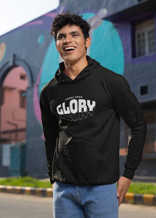 Man wearing a black hoodie with 'GLORY' text, standing in front of colorful graffiti art.