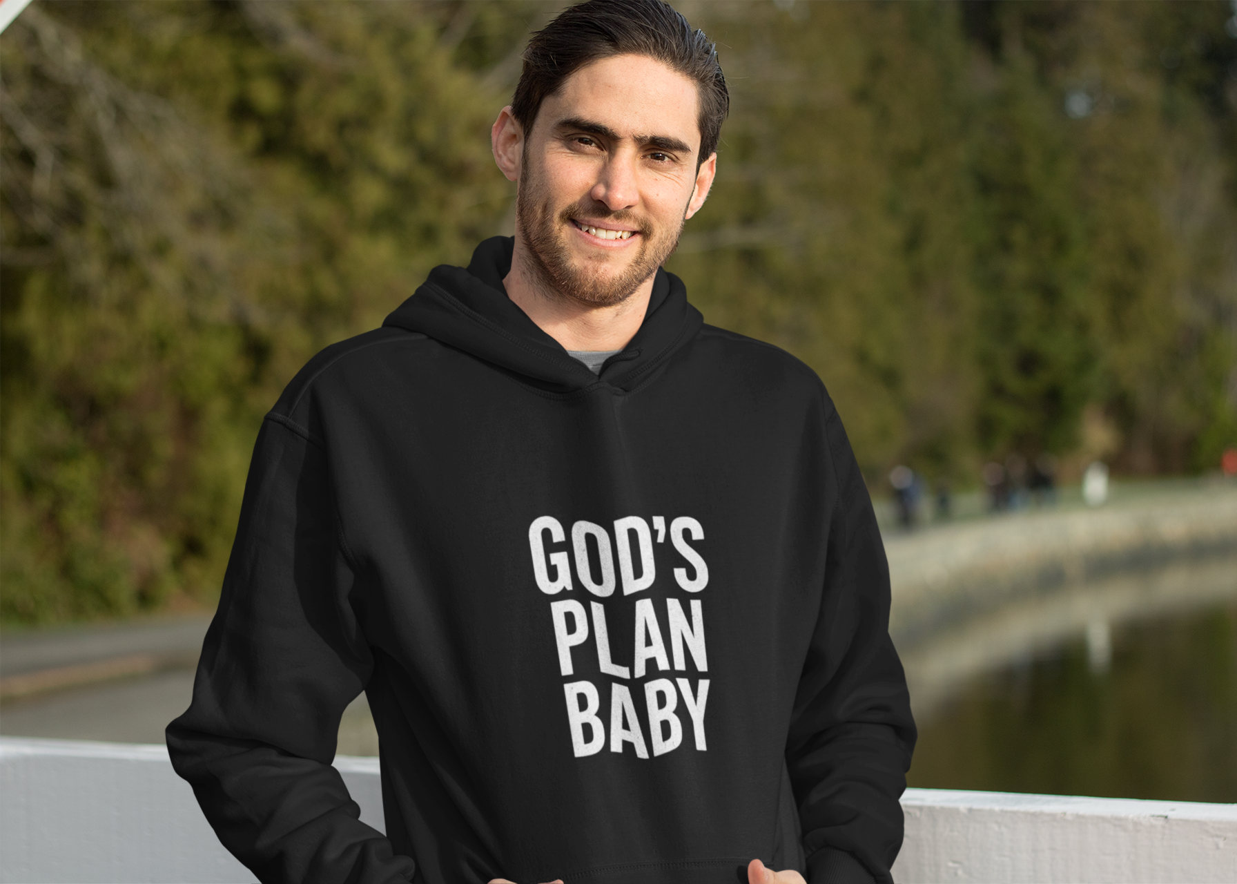 Man wearing a black hoodie with 'GOD'S PLAN BABY' text outdoors.
