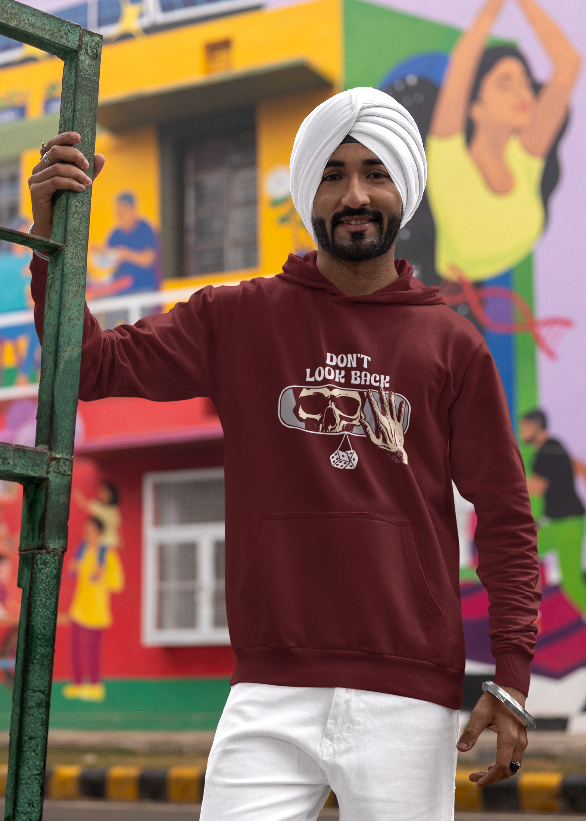 Man wearing a maroon hoodie with text, standing in front of a colorful mural.